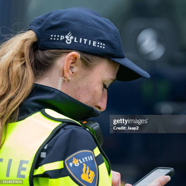 female dutch police officer in uniform looking down on het smartphone - dutch language stock pictures, royalty-free photos & images