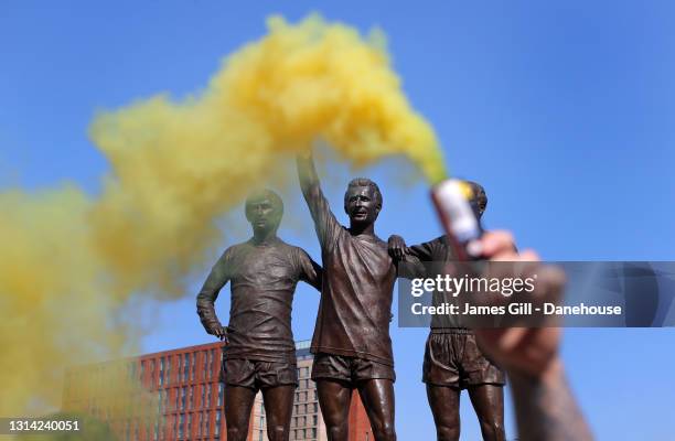 Flares are let off around the Holy Trinity statue of Sir Bobby Charlton, Denis Law and George Best as Manchester United supporters protest against...