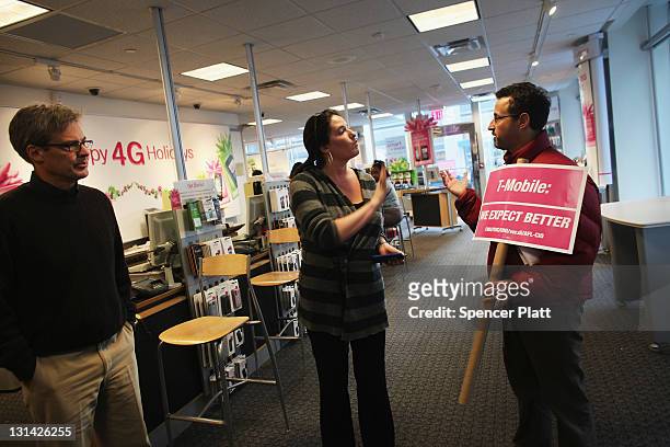 Member of the the Communication Workers of America speaks with a T-Mobile employee during a demonstration by Occupy Wall Street protestors and...