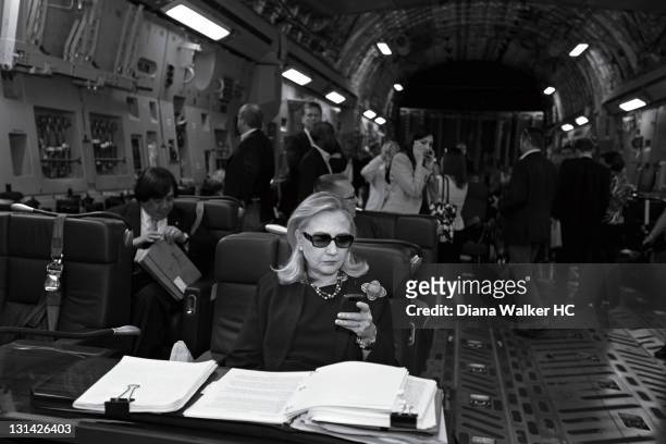 Secretary of State Hillary Clinton, aboard a C-17, checking her PDA in sunglasses upon departure from Malta bound for a meeting with rebel leaders in...