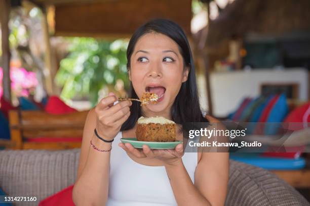 malaysian female food blogger tasting carrot cake at a holiday villa - taste test stock pictures, royalty-free photos & images