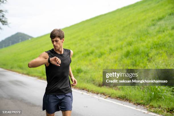 millennial man working out with fitness bracelet - running man heartbeat stock pictures, royalty-free photos & images