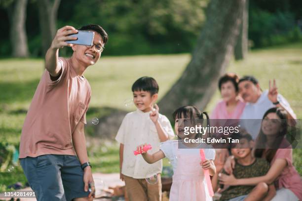 asian chinese multi generation family enjoying selfie photography using smart phone at picnic outdoor park - chinese family taking photo at home stock pictures, royalty-free photos & images