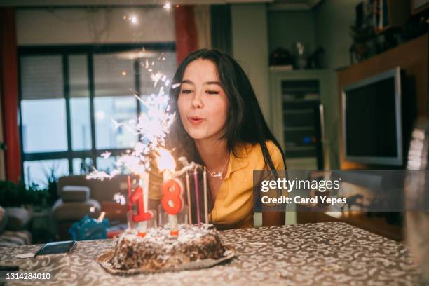 teenager latina blowing out candles in her birthday at homeowing out candles on a birthday cake - happy birthday vintage - fotografias e filmes do acervo