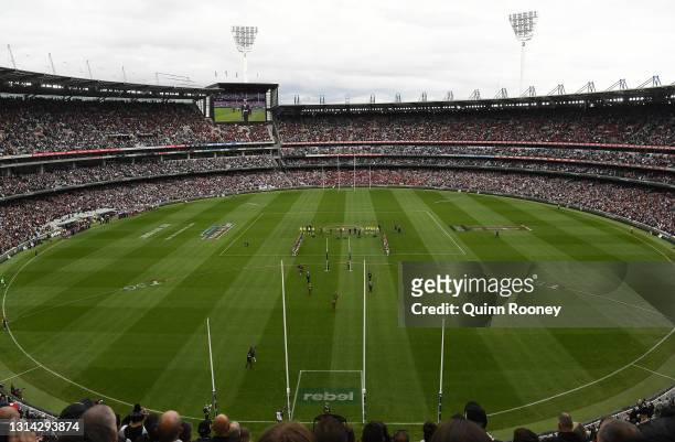 The crowd stand for the Last Post during the round six AFL match between the Collingwood Magpies and the Essendon Bombers at Melbourne Cricket Ground...
