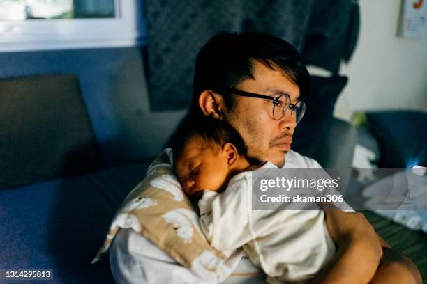 asian single father holding duaghter infant on his chest and feeling exhausted at late at night - spilt milk stock-fotos und bilder