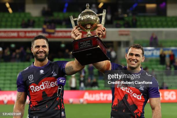 Jesse Bromwich of the Storm and Dale Finucane of the Storm holds aloft the Michael Moore trophy after winning the round seven NRL match between the...