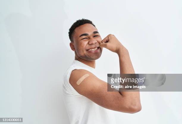 short haired man wearing a white shirt smiling and flexing his arm - flexing muscles stockfoto's en -beelden