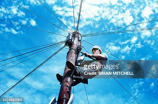 Telegraph lineman working on a telegraph pole picture against a blue sky