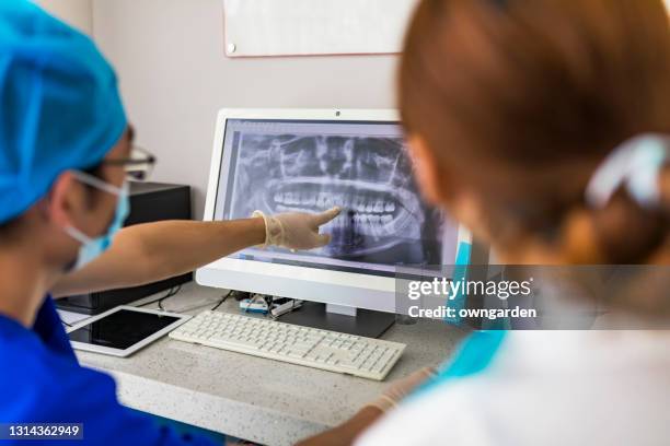 dentist shows the patient an x-ray image at display. computer diagnostics dental tomography. planning teeth treatment in modern dental clinic. - dentalimplantat stock-fotos und bilder