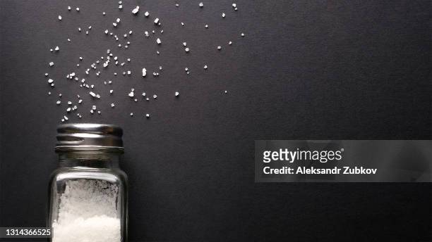natural, organic, sea, white salt, poured from a fallen salt shaker, on a black table or background. the concept of cooking healthy food, cosmetology. copy of the text space. - gesalzenes stock-fotos und bilder