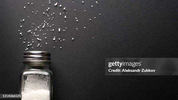 natural, organic, sea, white salt, poured from a fallen salt shaker, on a black table or background. the concept of cooking healthy food, cosmetology. copy of the text space. - salt and pepper shaker stock pictures, royalty-free photos & images