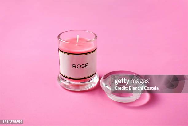 scented rose candle on pink background - scented candle stock-fotos und bilder