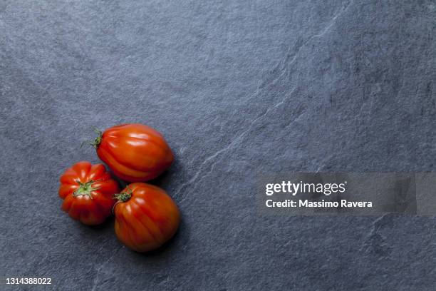 red tomatoes on dark stone surface - red texture stockfoto's en -beelden