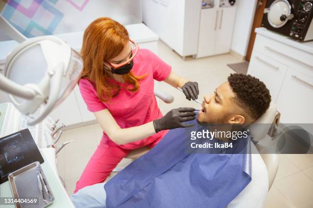 young african-american man at dental office - dental hygienist stock pictures, royalty-free photos & images