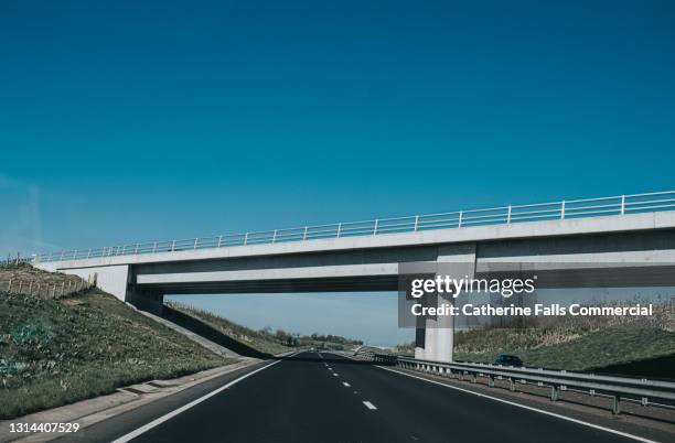 large concrete bridge over a motorway - straßenüberführung stock-fotos und bilder