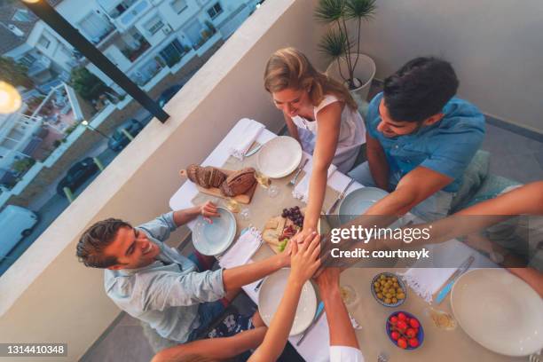 gente del grupo tomado de la mano en una cena. - friends sharing mediterranean fotografías e imágenes de stock