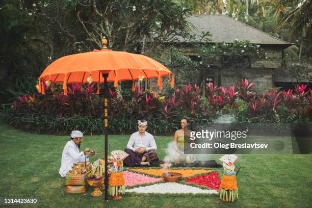 european couple on traditional bali wedding ritual blessing ceremony with balinese monk - balinese culture stock-fotos und bilder
