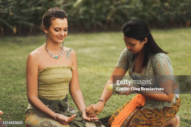 balinese woman in traditional clothing holds blessing wedding ceremony with sacred accessories for european caucasian couple in bali - ceremony imagens e fotografias de stock