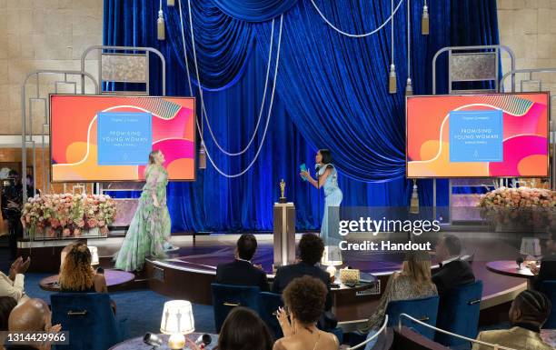 In this handout photo provided by A.M.P.A.S., Emerald Fennell accepts the Writing award for 'Promising Young Woman' from Regina King onstage during...
