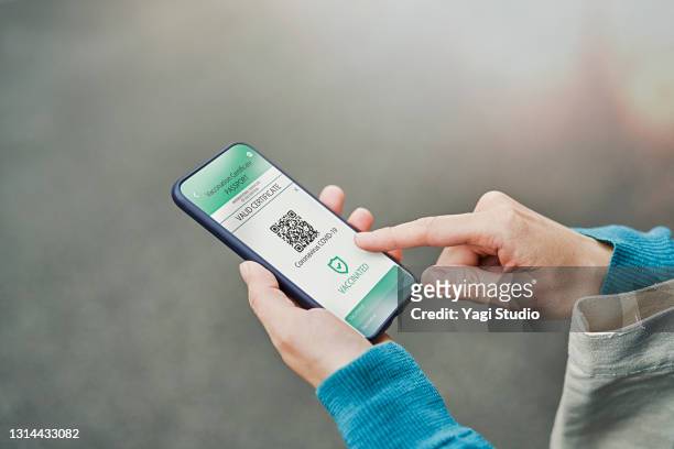 mid adult woman using a digital vaccine passport with smart phone in outdoor. - ブラックベリー ストックフォトと画像