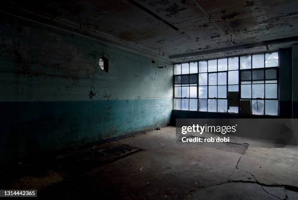 empty space with windows inside a decaying abandoned industrial factory - abandoned factory stock-fotos und bilder