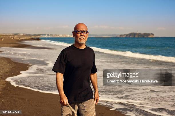 seniors spending time on beach - asian man barefoot foto e immagini stock