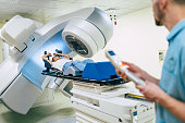Cancer treatment in a modern medical private clinic or hospital with a linear accelerator. Professional doctors team working while the woman is undergoing radiation therapy for cancer