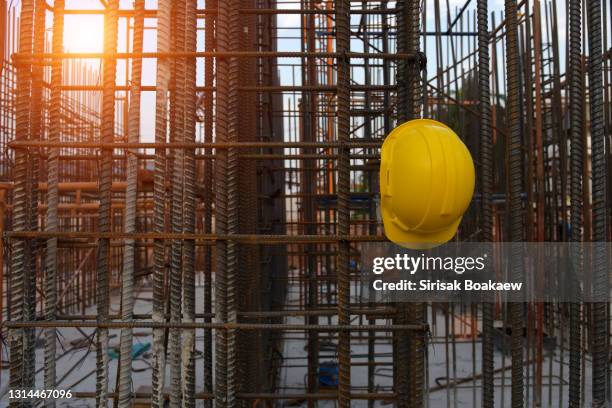 yellow helmet and blueprint at a construction site with a sunny background helmet - siniestro fotografías e imágenes de stock