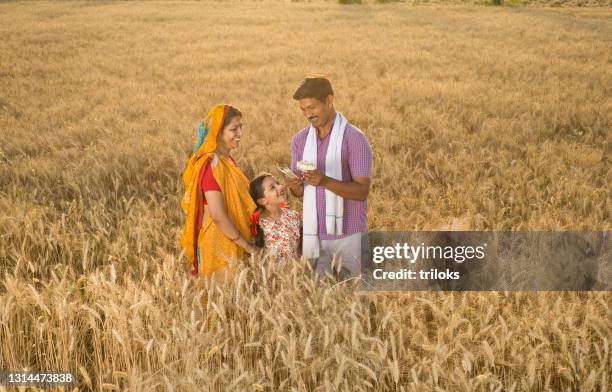 family with man holding indian rupee notes on agricultural field - farmers insurance stock pictures, royalty-free photos & images