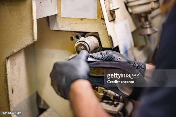 cobbler polishing high heel sole on machine in repair shop - footwear manufacturing stock pictures, royalty-free photos & images