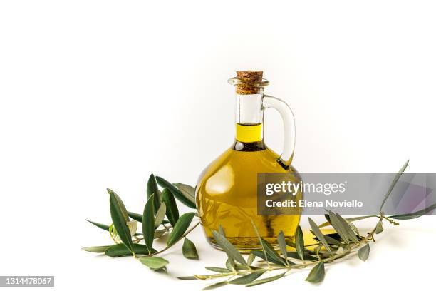 fresh extra virgin olive oil in a bottle, green olives and olive tree branches isolated on white background - olijfolie stockfoto's en -beelden