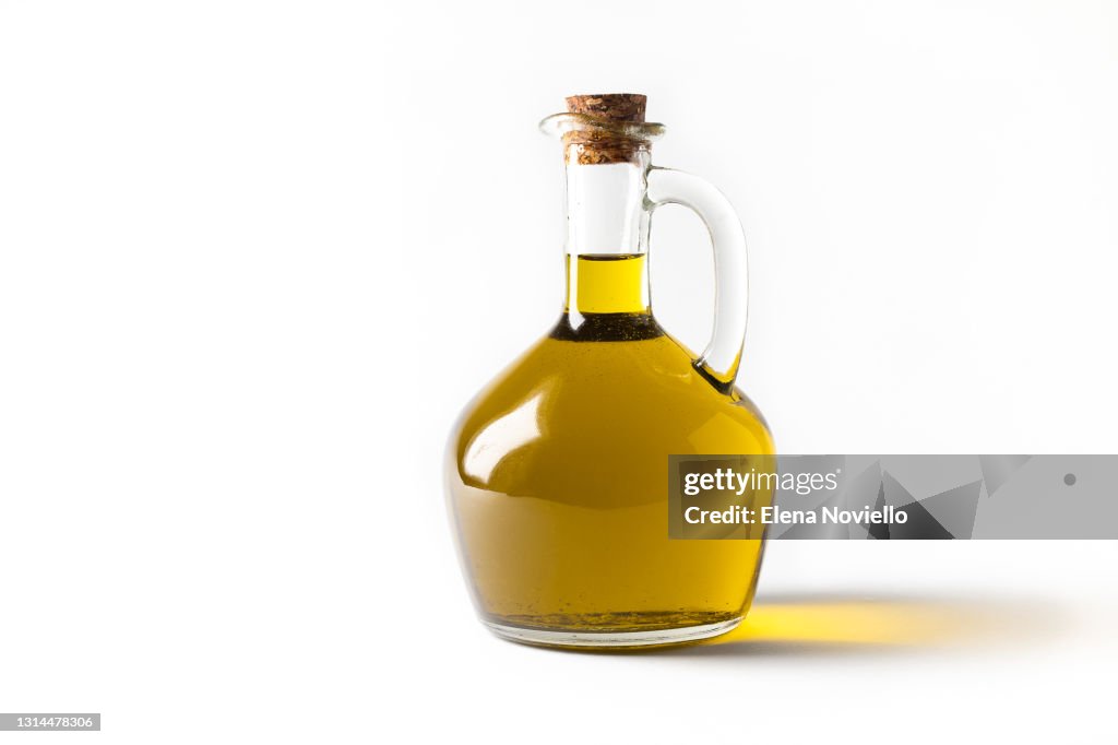 Fresh extra virgin olive oil in a bottle, green olives and olive tree branches isolated on white background