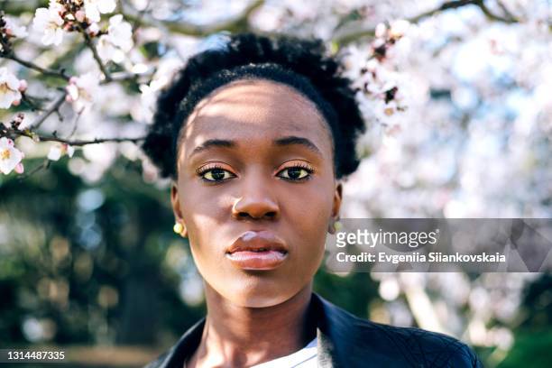 beautiful young black girl against blossom spring trees. - nature tree black white stock-fotos und bilder