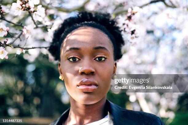 beautiful young black girl against blossom spring trees. - women serious face photos et images de collection