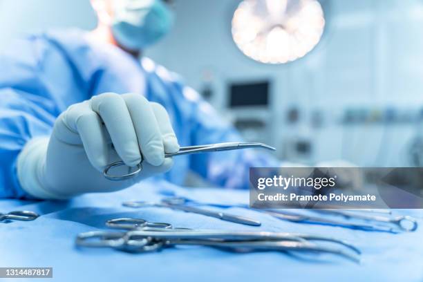 hand of assistant nurse hand taking surgical instrument to surgeons in operating room patient, steel medical instruments ready to be used. surgeon equipment concept - equipo quirúrgico fotografías e imágenes de stock