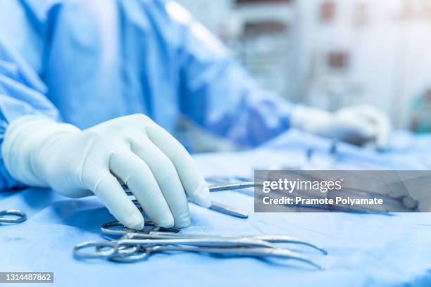 hand of assistant nurse hand taking surgical instrument to surgeons in operating room patient, steel medical instruments ready to be used. surgeon equipment concept - operating room ストックフォトと画像