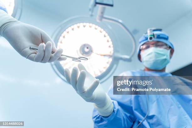 close up hand of doctor or surgeon working inside modern operating room.  scrub nurse sending surgical scissors to surgeon.  focus at instrument with intention to blurred background. - neurosurgery stock-fotos und bilder