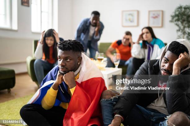 a sad group of friends watch the television in disappointment - sports man cave stock pictures, royalty-free photos & images