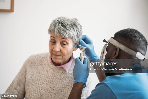 an older woman having her ears checked by the ear doctor - inner ear stock pictures, royalty-free photos & images