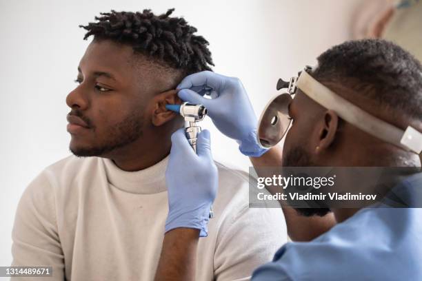 a medical professional is checking the patient's ears - inner ear stock pictures, royalty-free photos & images
