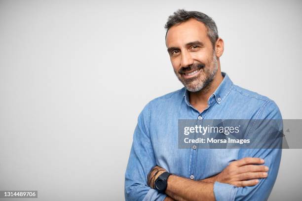 confident hispanic man against white background - blauw shirt stockfoto's en -beelden