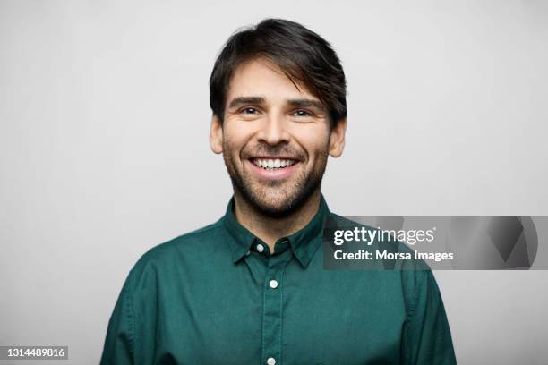 smiling hispanic man against gray background - grünes hemd stock-fotos und bilder