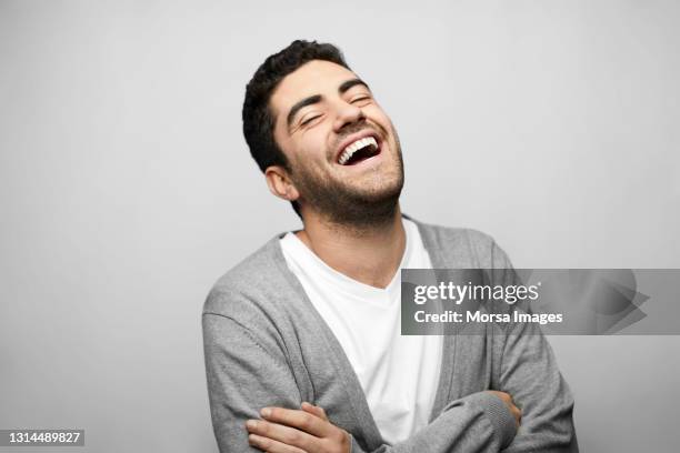 laughing latin american man against gray background - laughing fotografías e imágenes de stock