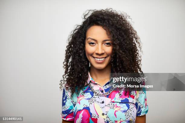 smiling hispanic woman against gray background - multi colored shirt foto e immagini stock