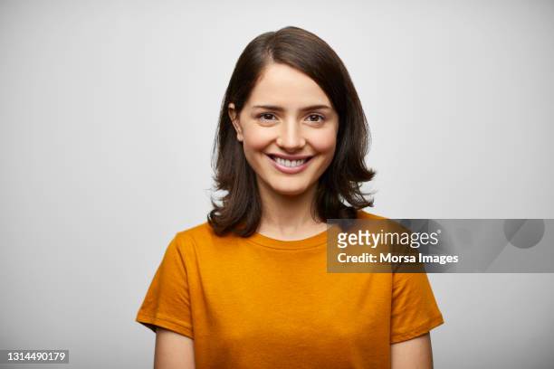 happy hispanic woman against white background - woman with orange photos et images de collection