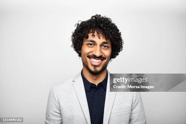 smiling latin american businessman against gray background - grey jacket stockfoto's en -beelden