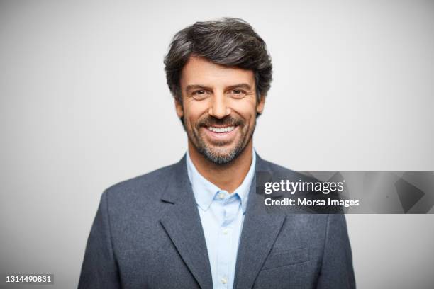 smiling hispanic businessman against white background - grey blazer stock-fotos und bilder