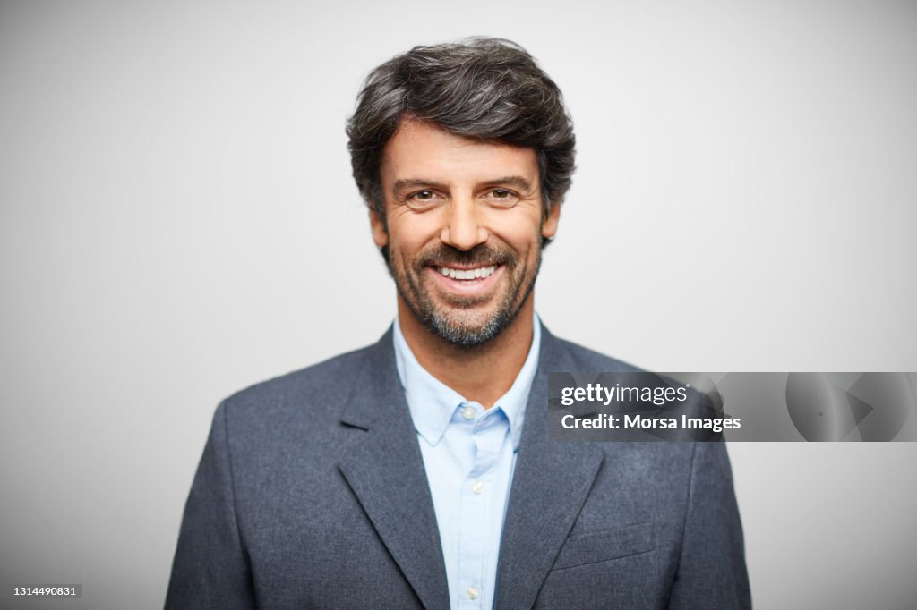 Smiling Hispanic Businessman Against White Background