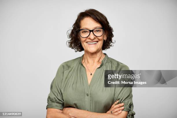 smiling elderly hispanic woman against gray background - portrait stock-fotos und bilder